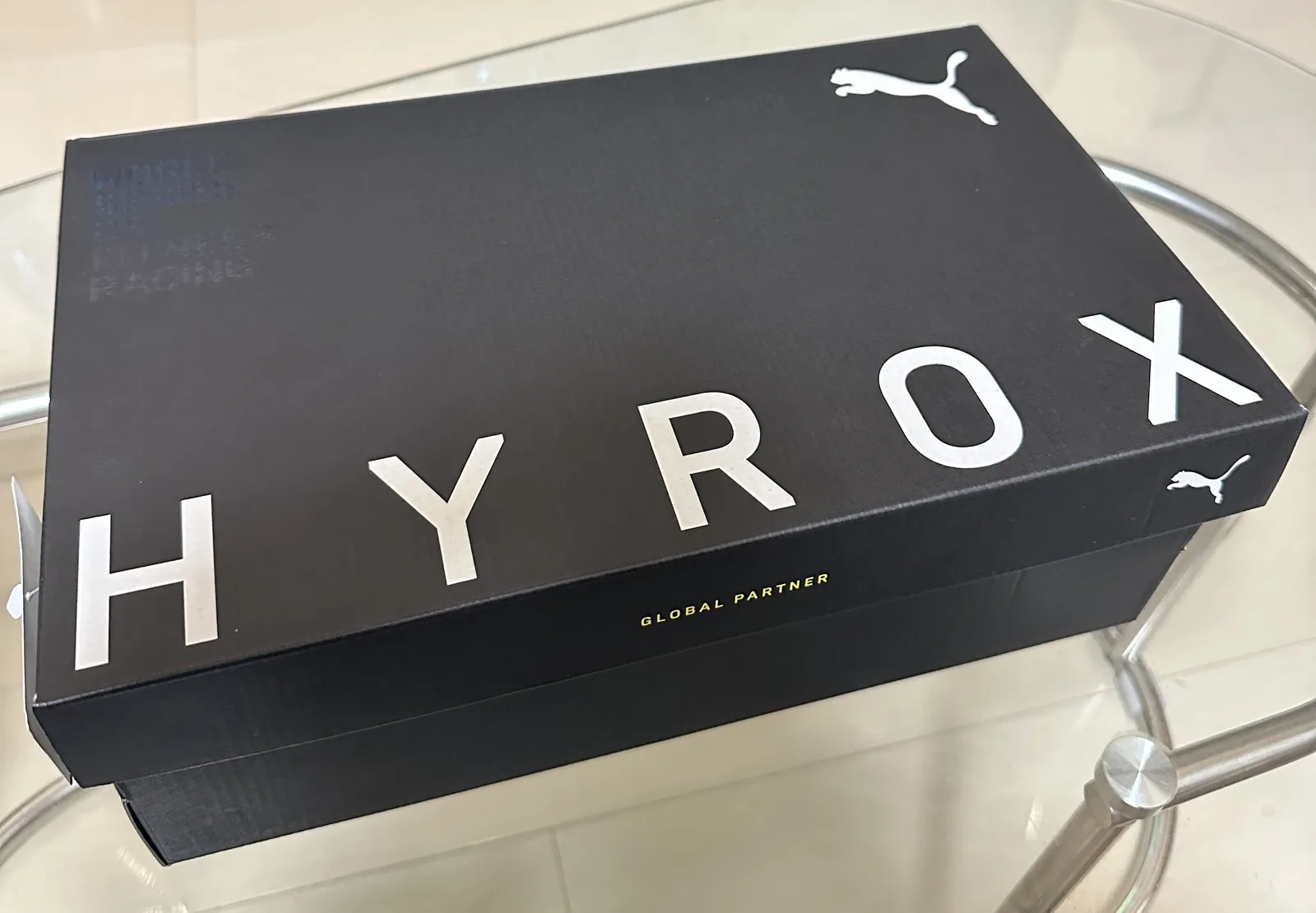 黒い靴箱の写真。フタに白い大きな文字でHYROXと書かれ、右上にPUMAのロゴ、側面にGLOBAL PARTNERの文字がある
