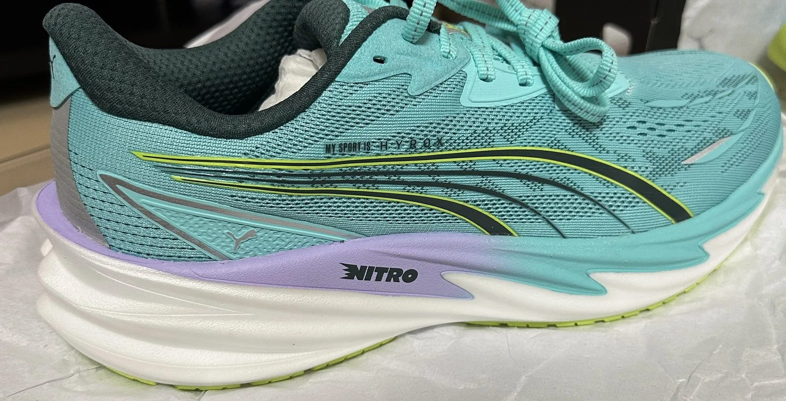 PUMA x HYROX ヴェロシティ ニトロ 5 の外側の側面の写真。ミントグリーンのアッパーに黒と黄緑のライン、MY SPORT IS HYROXの小さな文字、ミッドソールにNITROの表記がある